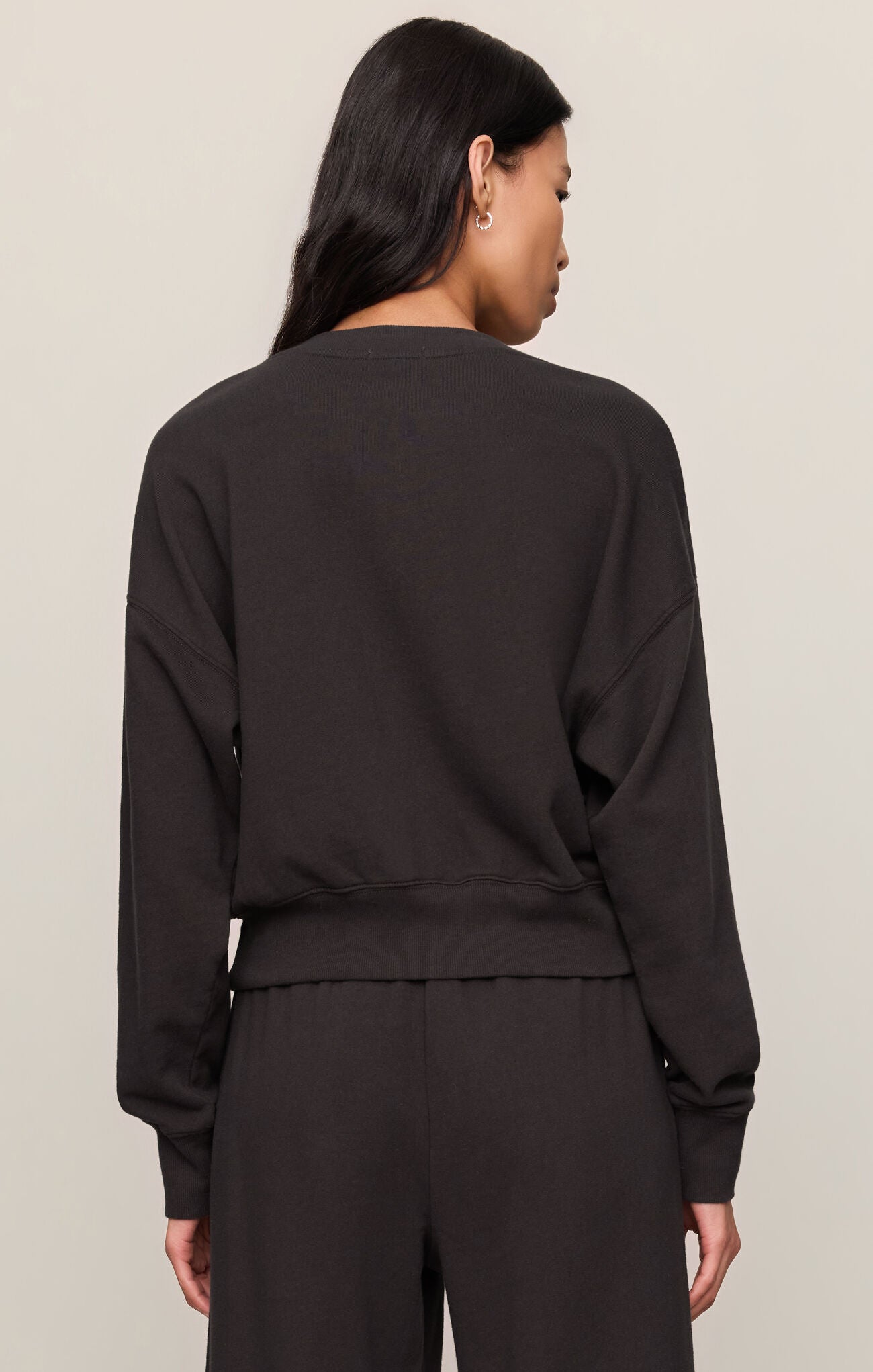 Person wearing a black outfit on a beige background
