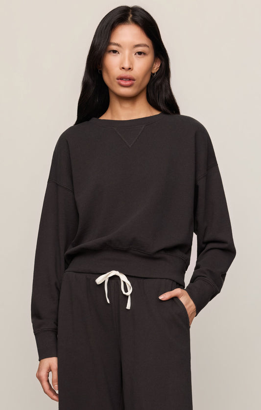 Woman wearing a black oversized sweatshirt and pants on a beige background