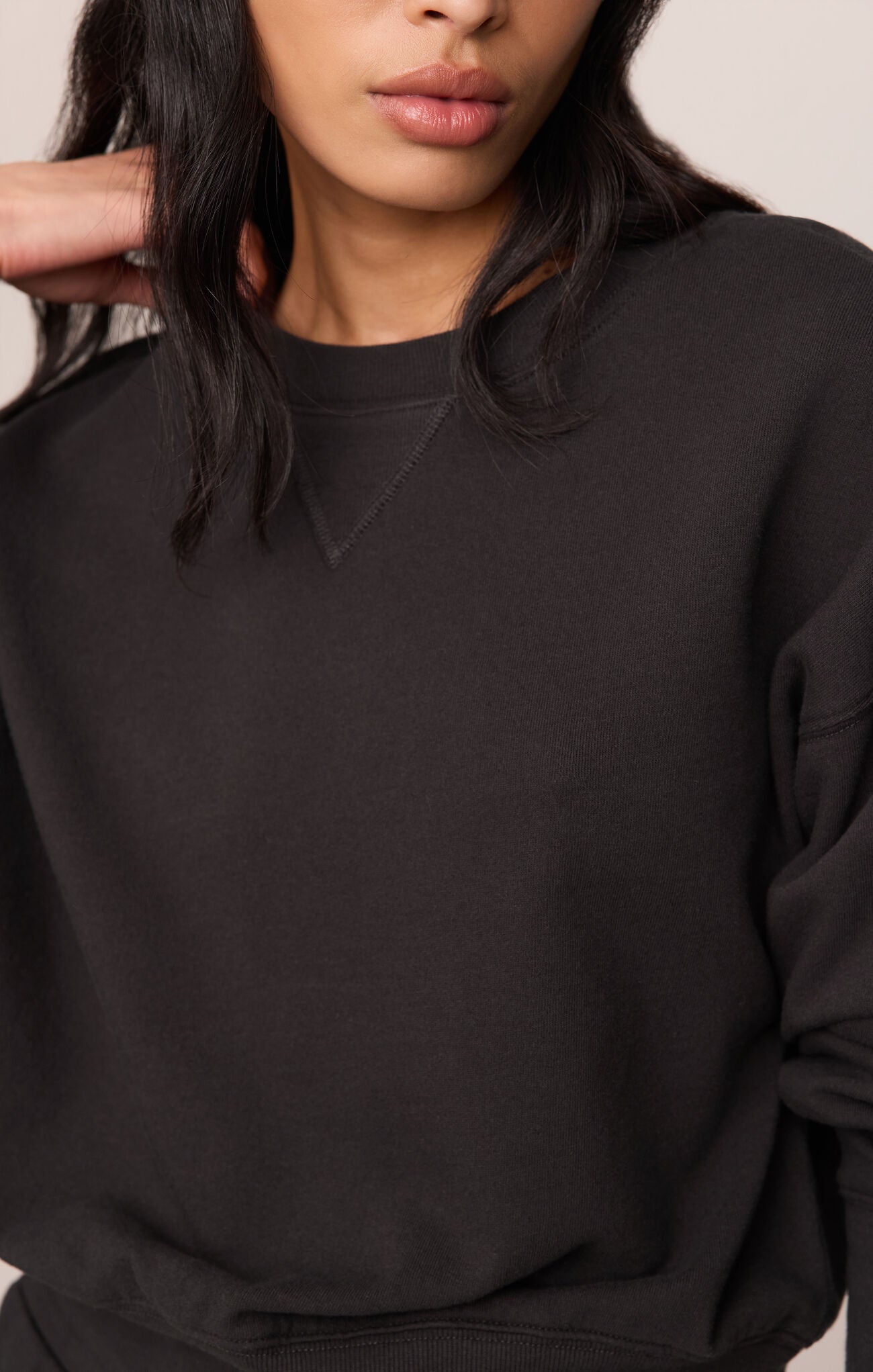 Person wearing a black sweatshirt against a neutral background