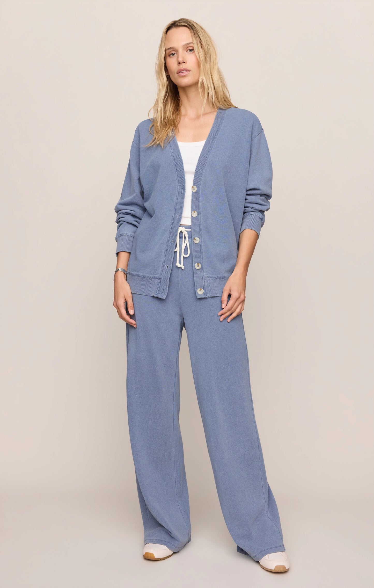 Woman wearing a blue outfit with a matching cardigan on a plain background