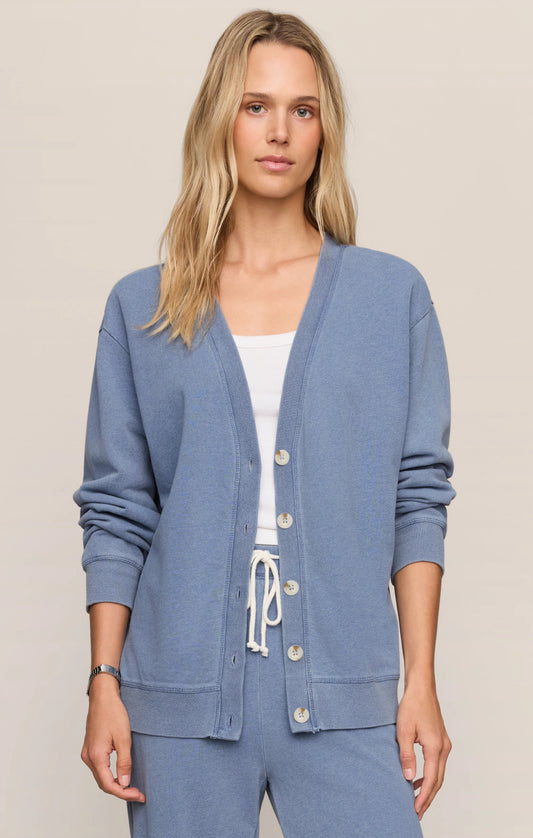 Woman wearing a blue cardigan over a white top on a beige background
